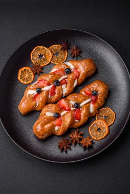 Koyu beton arka planda çilek ve yaban mersinli at kuyruğu şeklinde lezzetli çıtır kraker.