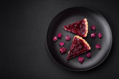 Koyu beton arka planda seramik tabakta kiraz meyveli lezzetli kokulu tatlı turta.