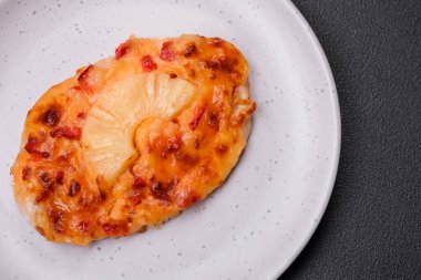 Izgara tavuk filetosu, domatesli biftek, ananas ve peynirli koyu beton arka planda.