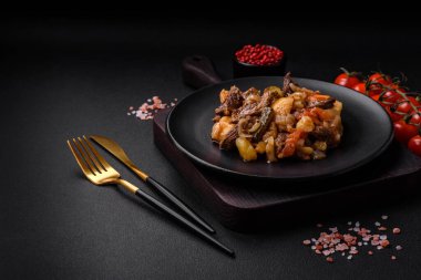 Patatesli, domatesli, biftekli, soğanlı ve havuçlu lezzetli güveç. Koyu beton arka planda seramik bir tabakta.