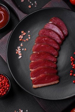 Lezzetli ördek fileto tütsülenmiş ya da baharat ve tuzla kızartılmış koyu beton arka planda.