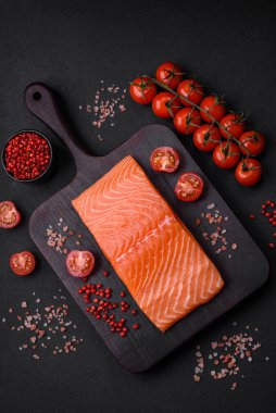 Taze çiğ somon balığı filetosu. Koyu beton arka planda tuz ve baharatla birlikte.