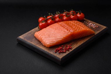 Taze çiğ somon balığı filetosu. Koyu beton arka planda tuz ve baharatla birlikte.