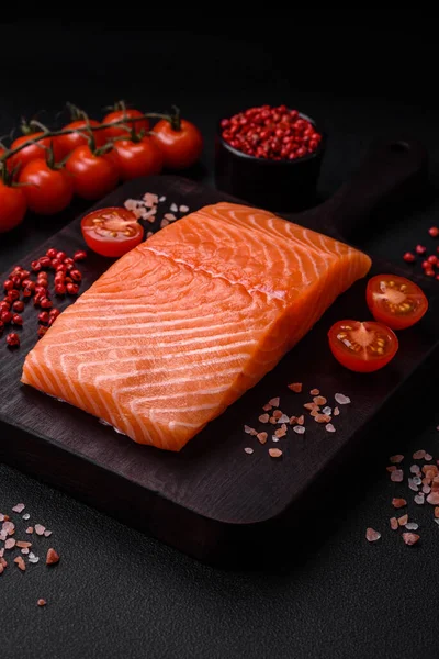 Taze çiğ somon balığı filetosu. Koyu beton arka planda tuz ve baharatla birlikte.