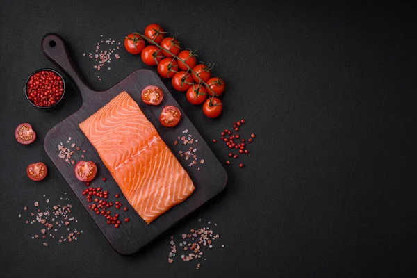 Taze çiğ somon balığı filetosu. Koyu beton arka planda tuz ve baharatla birlikte.