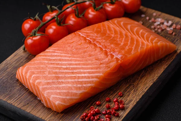 Taze çiğ somon balığı filetosu. Koyu beton arka planda tuz ve baharatla birlikte.