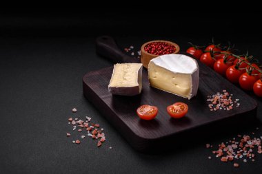 Koyu beton arka planda kiraz domatesli mini kafa şeklinde leziz taze brie peyniri.