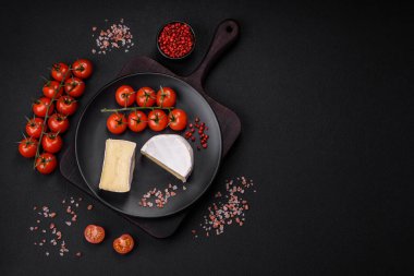 Koyu beton arka planda kiraz domatesli mini kafa şeklinde leziz taze brie peyniri.