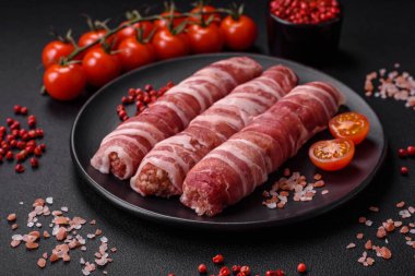 Pastırmaya sarılmış tuzlu ve baharatlı çiğ et veya koyu beton arka planda cevapcici.