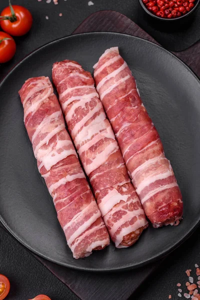 Pastırmaya sarılmış tuzlu ve baharatlı çiğ et veya koyu beton arka planda cevapcici.