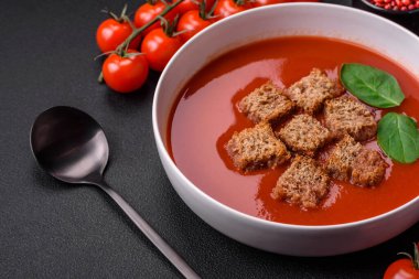 Koyu beton bir zeminde seramik tabakta ekmek kırıntıları, tuz ve baharatlarla nefis taze gazpacho.