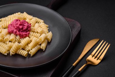 Beton arka planda pancar pesto, parmesan, tuz ve baharatlı lezzetli fusilli makarna.