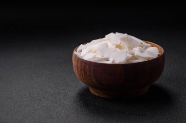 Tahta bir kasedeki beyaz hindistan cevizi taneleri beton kaplama bir zeminde tatlı yapmak için hazırlandı.