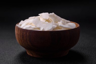 Tahta bir kasedeki beyaz hindistan cevizi taneleri beton kaplama bir zeminde tatlı yapmak için hazırlandı.