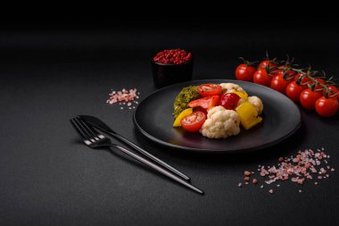 Lezzetli taze brokoli salatası, karnabahar, tatlı biber ve baharatlı kiraz domatesleri ve koyu beton arka planda tuz.