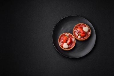 Çilekli taze turtalar ve koyu beton zeminde hindistan cevizi taneleri.