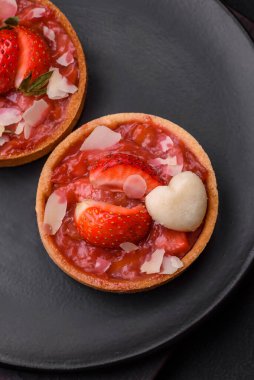 Çilekli taze turtalar ve koyu beton zeminde hindistan cevizi taneleri.