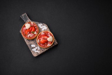 Çilekli taze turtalar ve koyu beton zeminde hindistan cevizi taneleri.