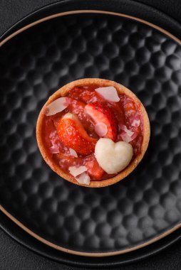 Çilekli taze turtalar ve koyu beton zeminde hindistan cevizi taneleri.