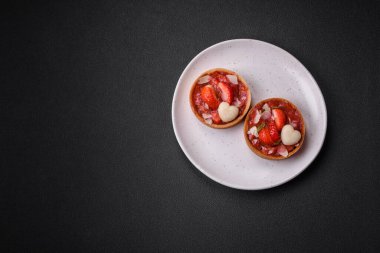 Çilekli taze turtalar ve koyu beton zeminde hindistan cevizi taneleri.