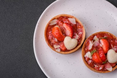 Çilekli taze turtalar ve koyu beton zeminde hindistan cevizi taneleri.