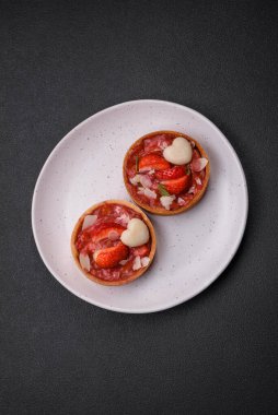 Çilekli taze turtalar ve koyu beton zeminde hindistan cevizi taneleri.