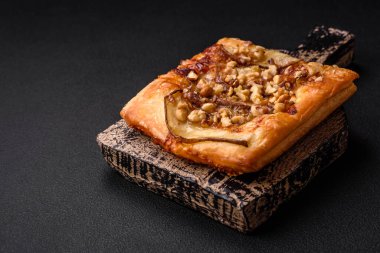 Lezzetli taze turta ya da armut, peynir, bal ve fındıklı koyu beton arka planda pizza.