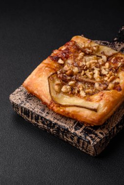 Lezzetli taze turta ya da armut, peynir, bal ve fındıklı koyu beton arka planda pizza.