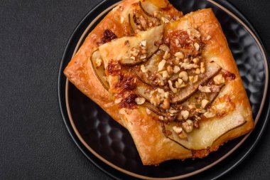 Lezzetli taze turta ya da armut, peynir, bal ve fındıklı koyu beton arka planda pizza.