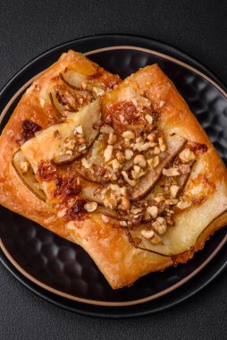 Lezzetli taze turta ya da armut, peynir, bal ve fındıklı koyu beton arka planda pizza.