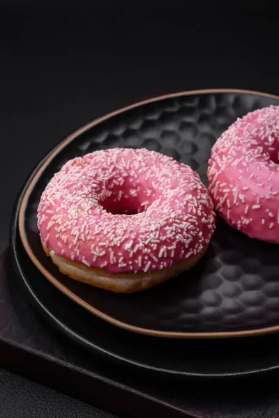 stock image Delicious fresh sweet donuts in pink glaze with strawberry filling on a dark concrete background