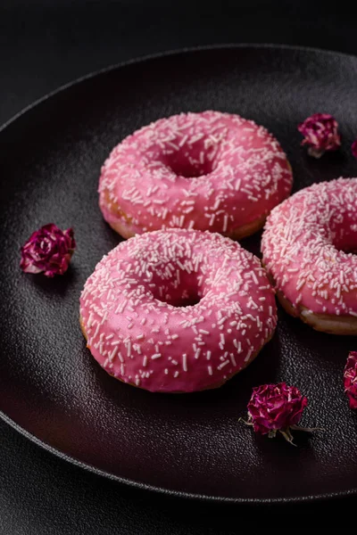 stock image Delicious fresh sweet donuts in pink glaze with strawberry filling on a dark concrete background