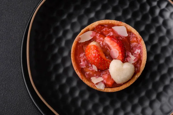 Çilekli taze turtalar ve koyu beton zeminde hindistan cevizi taneleri.