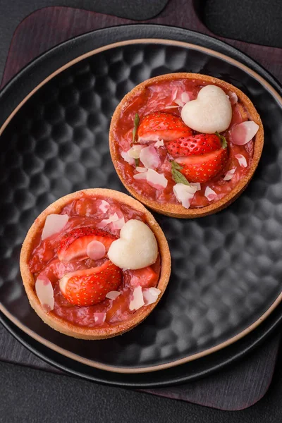 Çilekli taze turtalar ve koyu beton zeminde hindistan cevizi taneleri.