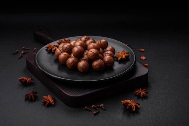 Lezzetli kavrulmuş macadamia fındıkları koyu desenli beton arka planda. Vejetaryen yemeği.