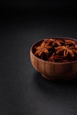 Yıldız şeklinde baharat yıldızı anason. Koyu beton arka planda ahşap yuvarlak bir kase içinde.