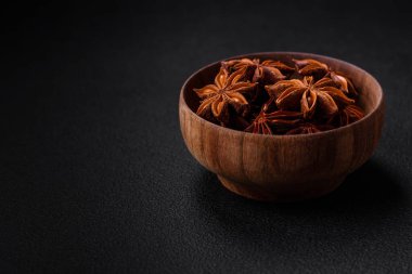 Yıldız şeklinde baharat yıldızı anason. Koyu beton arka planda ahşap yuvarlak bir kase içinde.