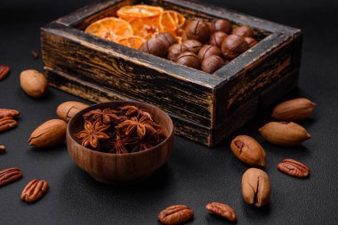 Kavrulmuş ceviz ve fındık, kurutulmuş mandalina, koyu beton arka planda kurutulmuş böğürtlen.