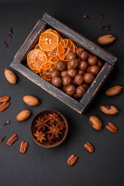 Kavrulmuş ceviz ve fındık, kurutulmuş mandalina, koyu beton arka planda kurutulmuş böğürtlen.