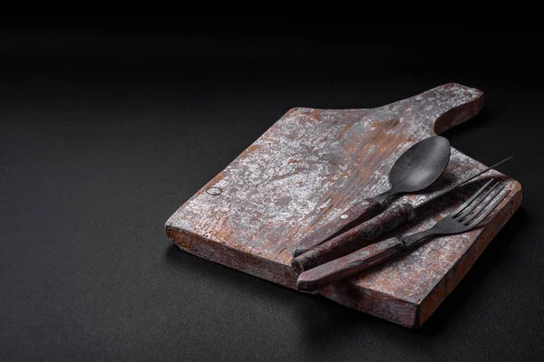 Bıçak, çatal ve kesim tahtası, tuz, biber ve diğer malzemeler desenli beton arka planda yer alıyor.