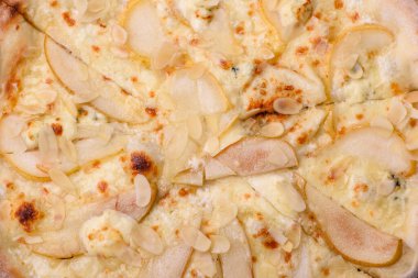 Armutlu lezzetli pizza, armut peyniri ve koyu beton arka planda fındık.