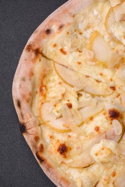 Armutlu lezzetli pizza, armut peyniri ve koyu beton arka planda fındık.