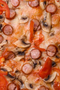 Füme sosisli Bavyera pizzası, domates, peynir, tuz ve baharatlar koyu beton arka planda.