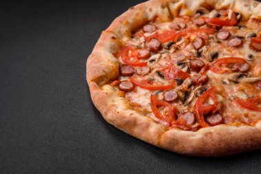 Füme sosisli Bavyera pizzası, domates, peynir, tuz ve baharatlar koyu beton arka planda.