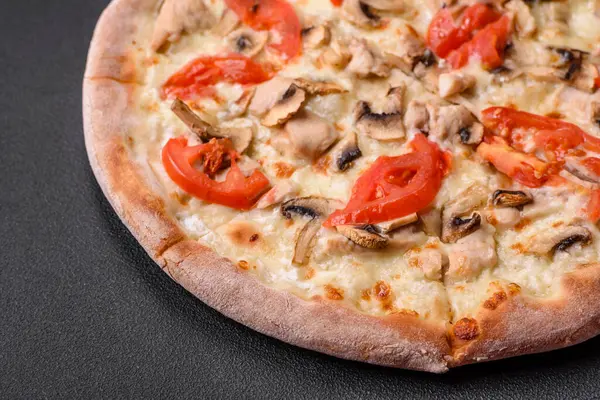 stock image Delicious pizza with chicken, tomatoes and cheese with salt and sauce on a dark concrete background