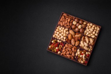 Kavrulmuş macadamia fındığı, ceviz, ceviz, ceviz, badem, kuru üzüm karışımı koyu beton bir arka planda.