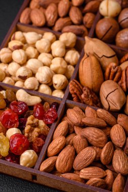 Kavrulmuş macadamia fındığı, ceviz, ceviz, ceviz, badem, kuru üzüm karışımı koyu beton bir arka planda.