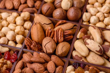 Kavrulmuş macadamia fındığı, ceviz, ceviz, ceviz, badem, kuru üzüm karışımı koyu beton bir arka planda.