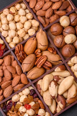 Kavrulmuş macadamia fındığı, ceviz, ceviz, ceviz, badem, kuru üzüm karışımı koyu beton bir arka planda.