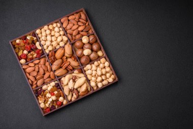 Kavrulmuş macadamia fındığı, ceviz, ceviz, ceviz, badem, kuru üzüm karışımı koyu beton bir arka planda.